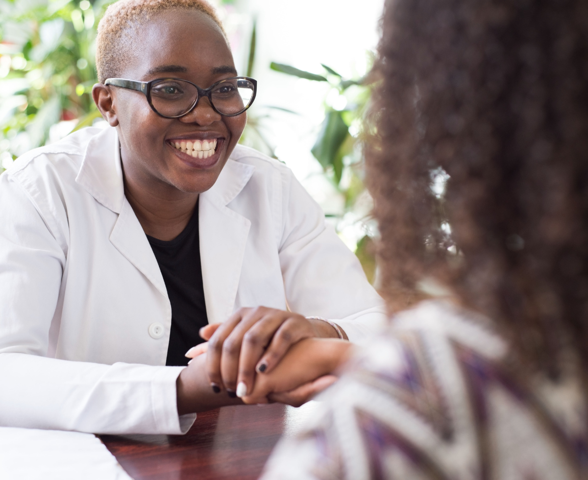 black medical provider with short hair holding the hand of a patient